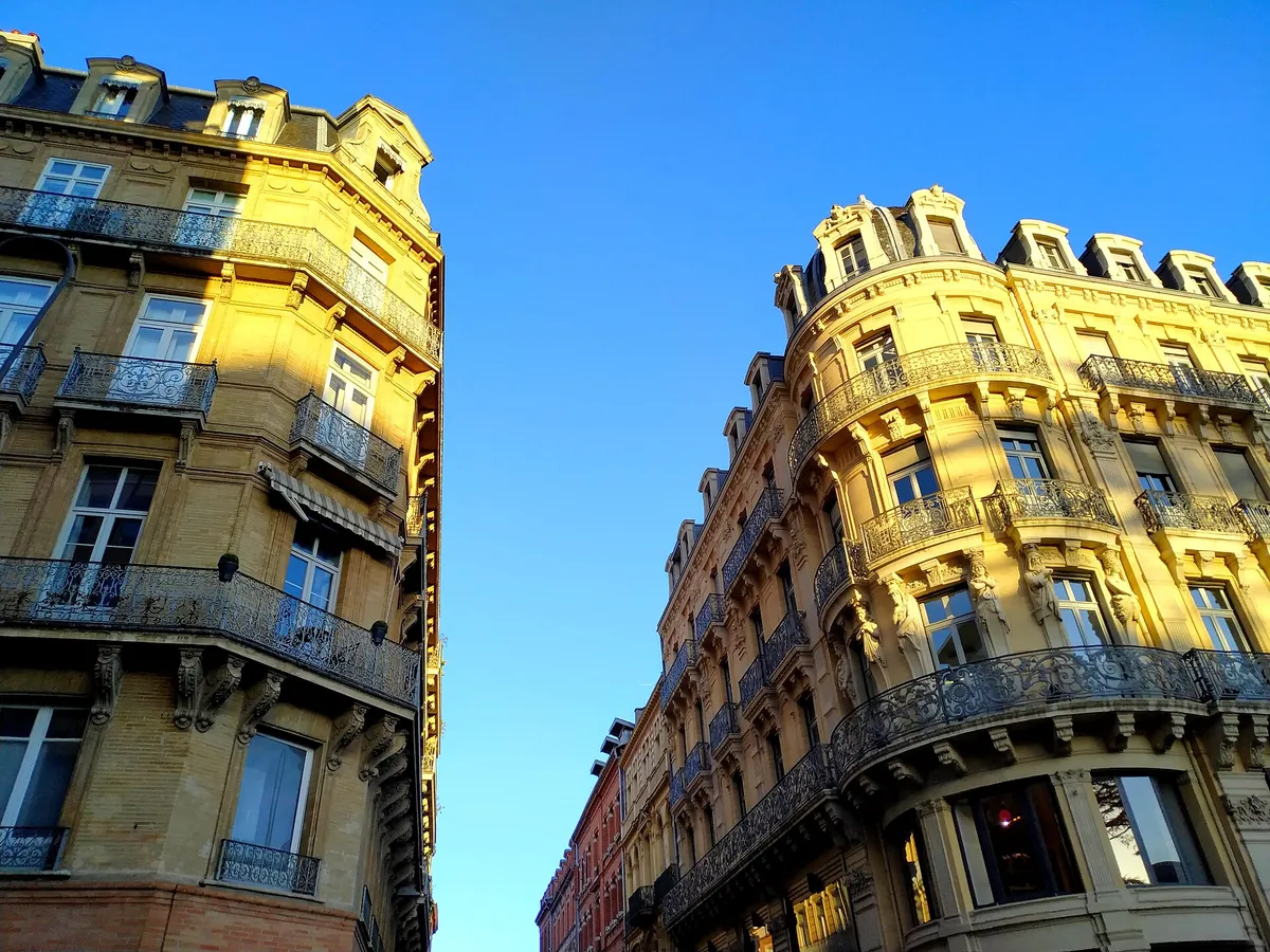 Immeubles en brique et pierre aux balcons en fer forgé dans une rue de Toulouse