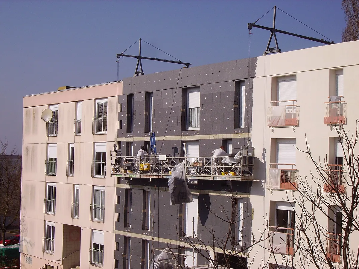 Chantier d'isolation thermique par l'extérieur sur la façade d'un immeuble de logements, panneaux isolants en cours de pose