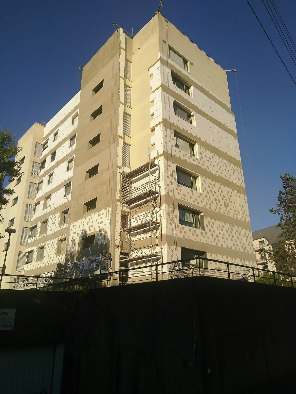 Immeuble résidentiel à Rennes en cours de rénovation thermique, façade partiellement recouverte d'isolant