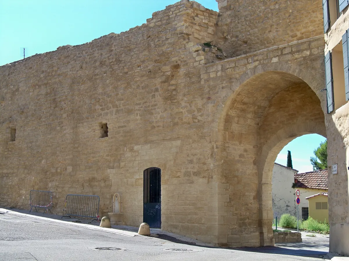 Remparts restaurés et porte voûtée du centre historique de Courthézon sous un ciel bleu