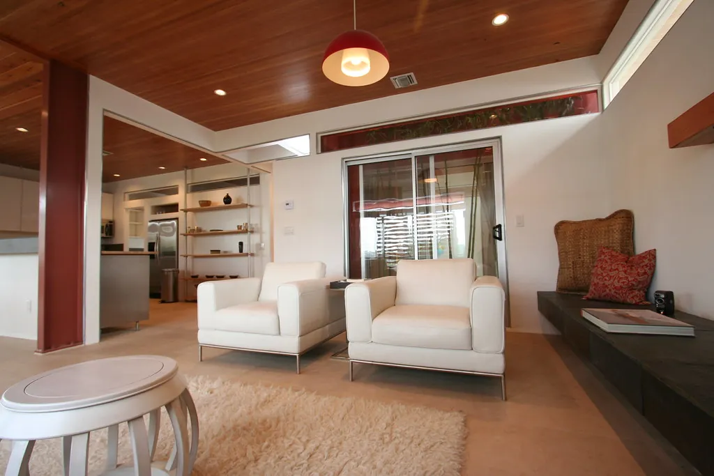 Salon lumineux avec fauteuils blancs et cuisine ouverte, type de photo d'annonce immobilière retouchable par intelligence artificielle