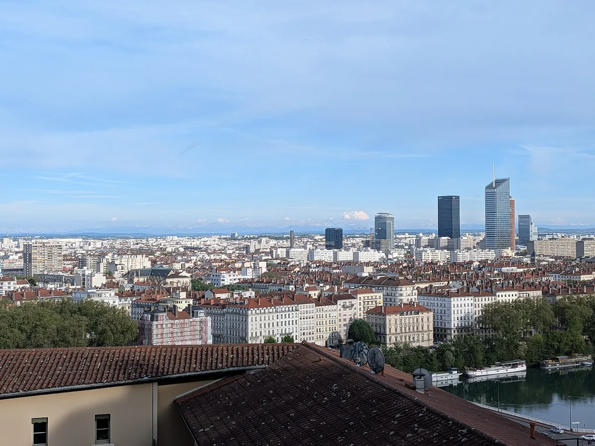 Immeubles du centre de Lyon et tours de la Part-Dieu vus depuis la place Bellevue, avec les Alpes à l'horizon