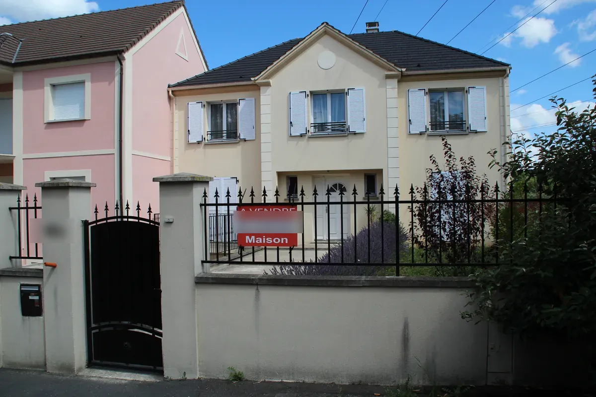 Maison individuelle avec un panneau à vendre accroché à la clôture, en Île-de-France
